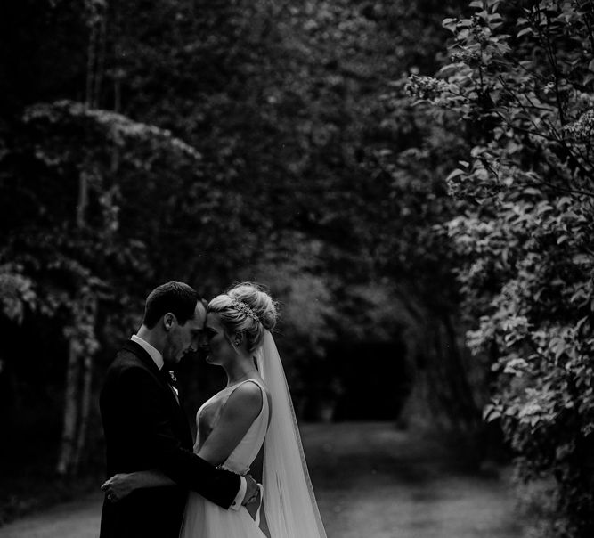 Bride in Stella York Wedding Dress and Cathedral Length Veil and Groom in Navy Suit Embracing