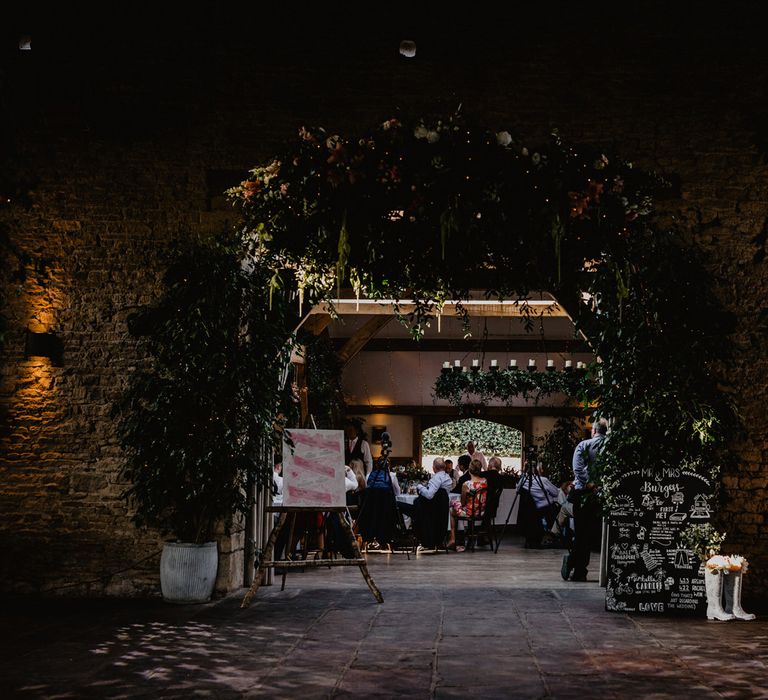 Cripps Barn Wedding Reception Decor with Floral Chandelier, Chalkboard Sign and Wellington Boots