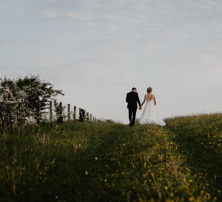 Bride and Groom Walking Through The Fields