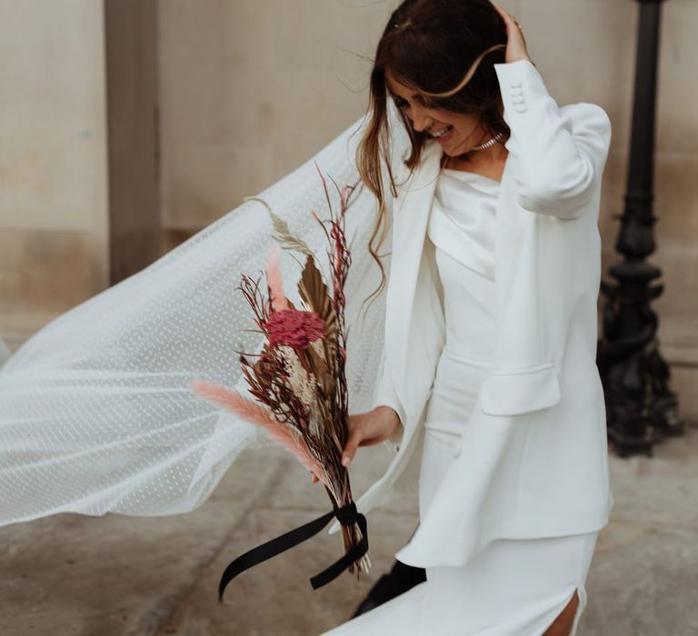 Bride wearing a statement pair of bright pink shoes with a  white blazer and dried pampas grass filled bouquet