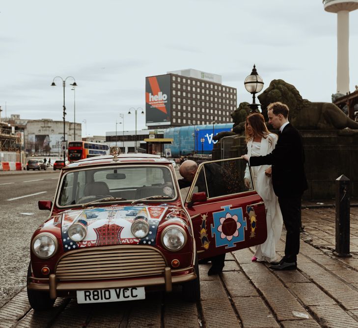 Bride and groom travel in style to their wedding reception in a personalised Mini Cooper