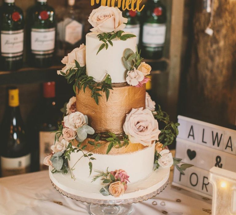 White and gold wedding cake with flower decor