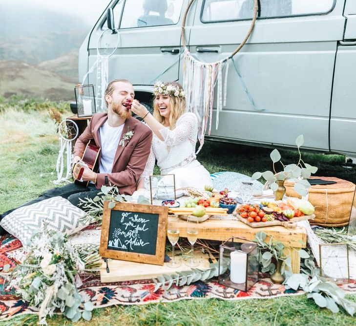 Boho Bride in Crochet Dress Feeding Her Groom Grapes from a Grazing Table