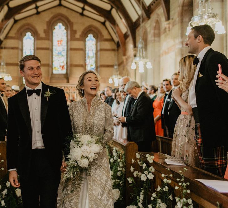 Bride and Groom Walk Back Down Aisle Laughing With Guests