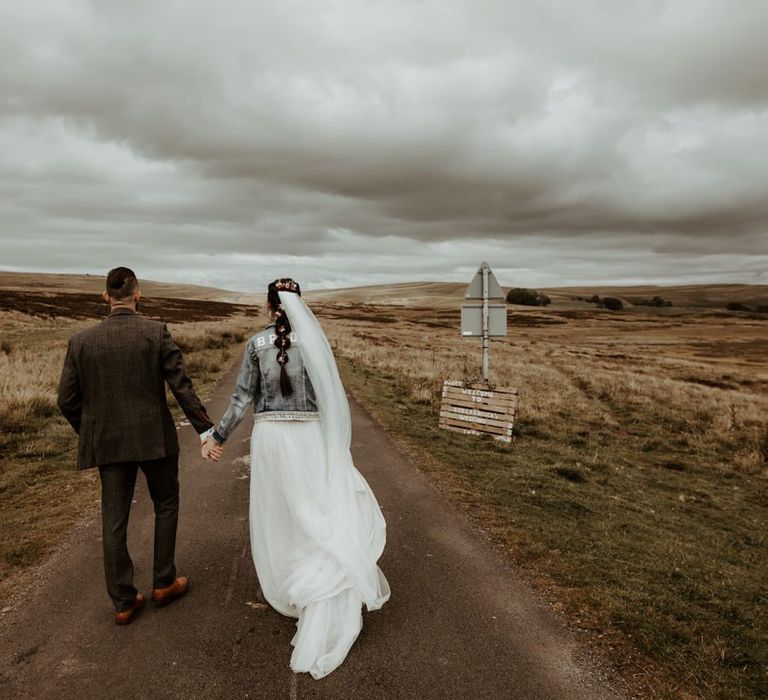 Groom in world suit and Bride in denim jacket walking in the Lake District