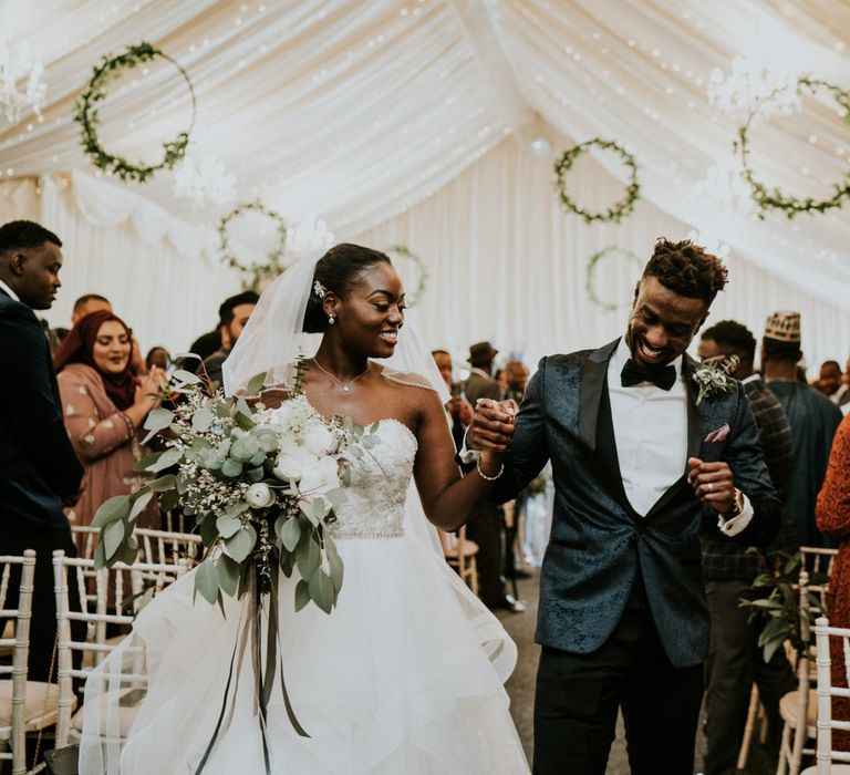 Bride and groom at marquee ceremony with wooden wedding signs and hoop decor