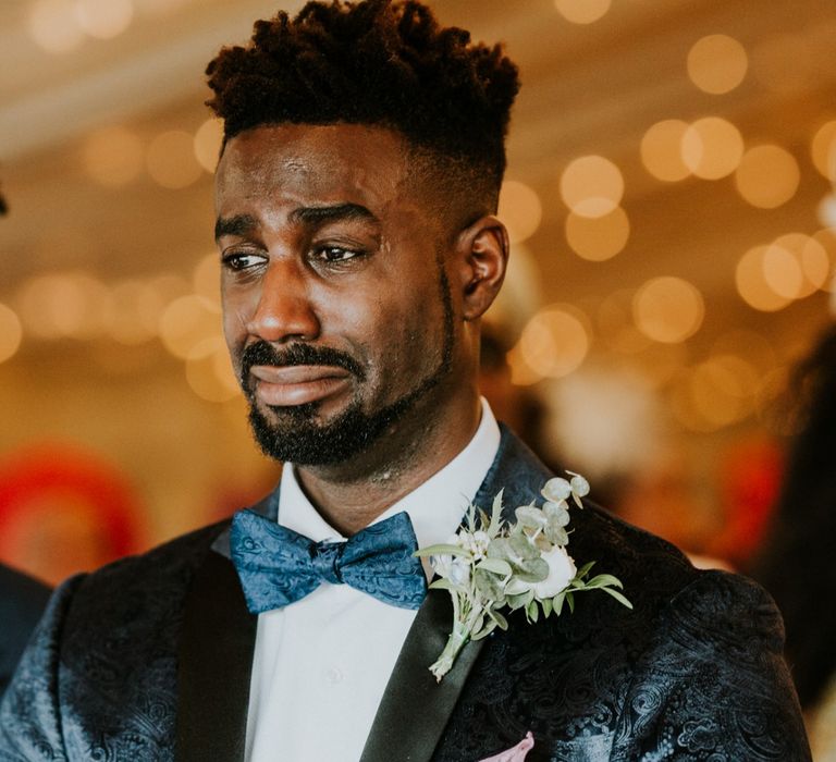 Groom in blue bowtie gets emotional during wedding ceremony