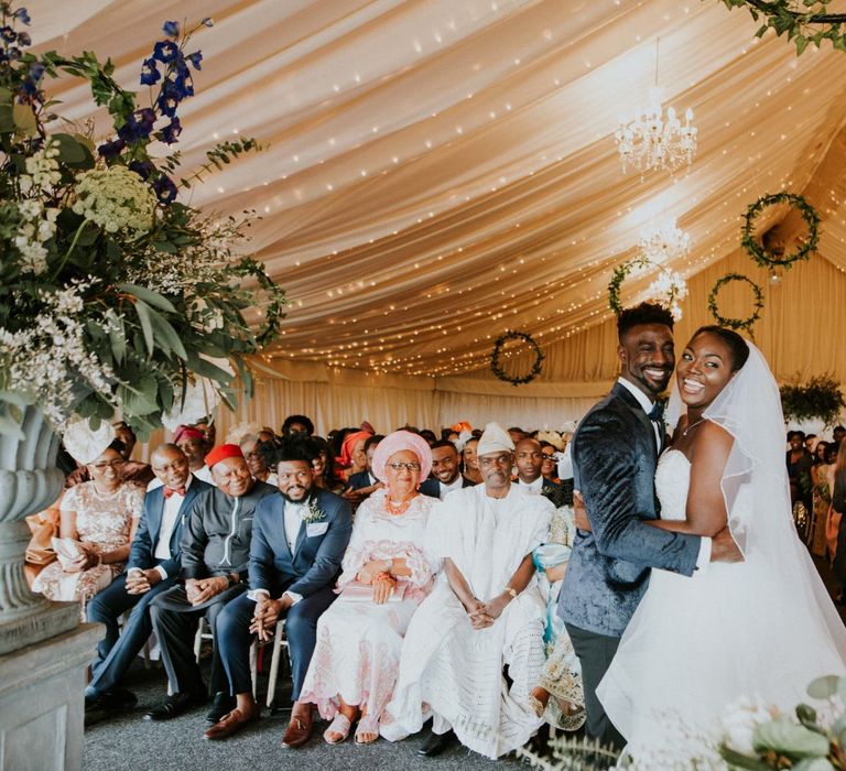 Bride and groom at marquee ceremony with wooden wedding signs and hoop decor