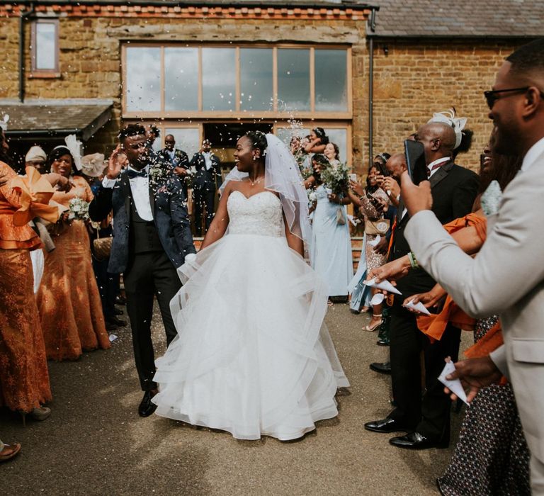 Confetti exit for bride in strapless wedding dress and groom in blue dinner jacket