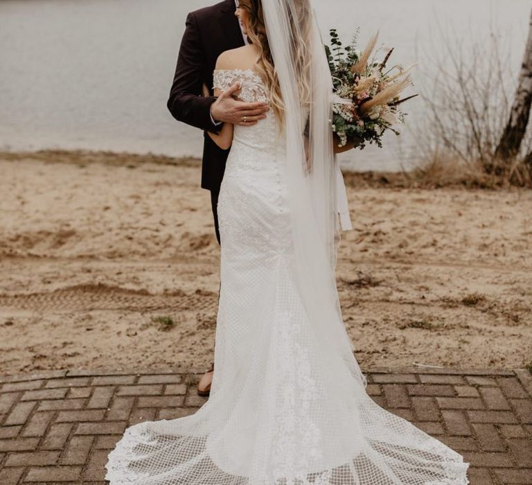 Groom in brown wedding suit with bride holding dried bouquet