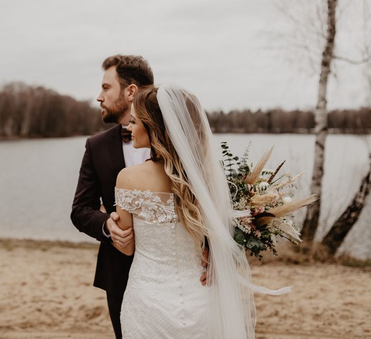 Groom in brown wedding suit with bride holding dried bouquet