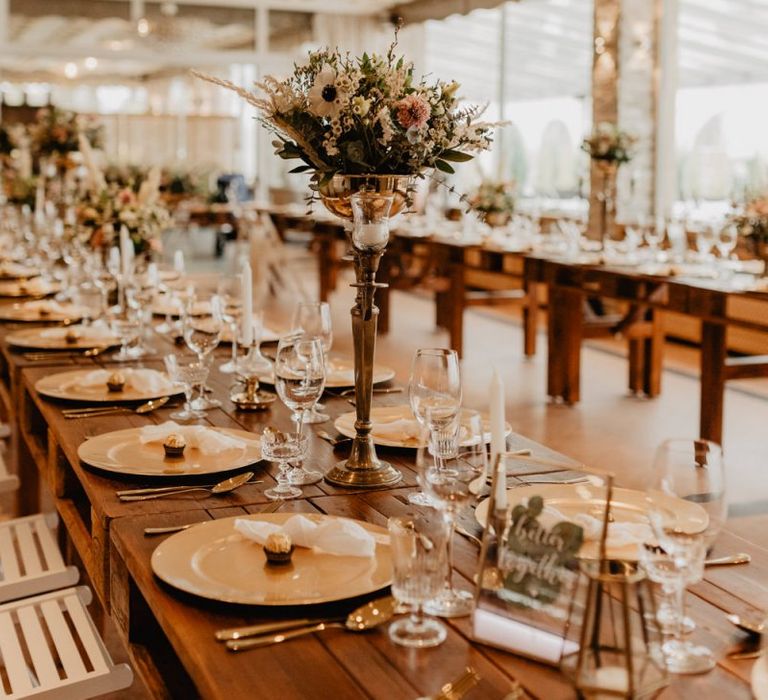 Tall flower centrepieces on long banquet tables for boho wedding