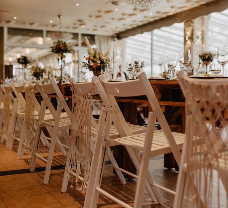 Tall flower centrepieces on long banquet tables for boho wedding