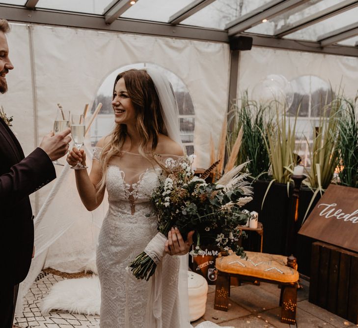 Groom in brown wedding suit toasts the day with new wife