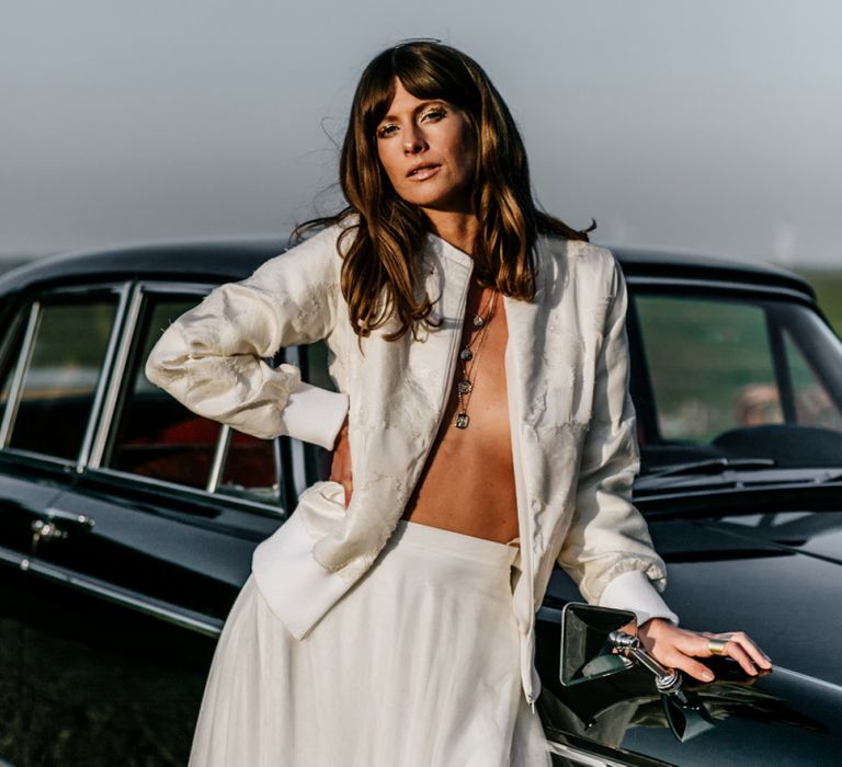 Boho Bride with Sweeping Fringe Leaning Up Against a Wedding Car