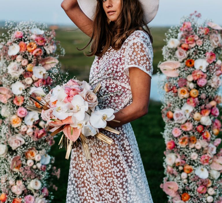 Bohemian Bride in Lace Wedding Dress and Floppy Hat Holding a Blush Pink and white Flower Bouquet