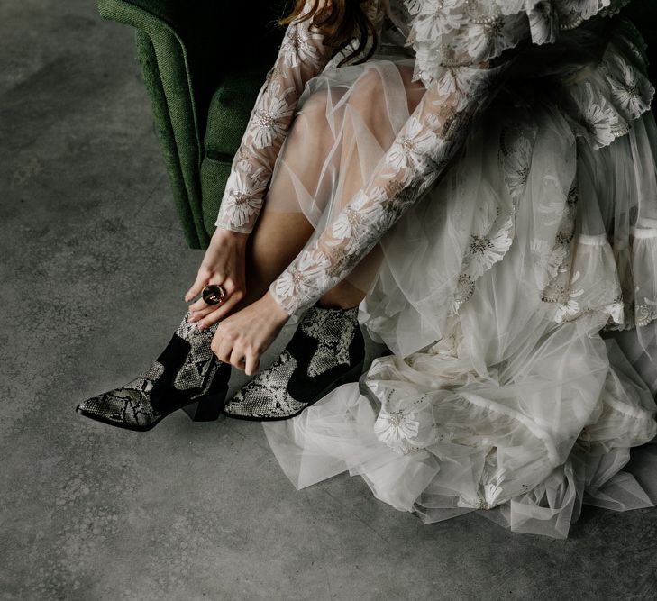 Bride in Lace Wedding Dress Putting on Snakeskin Bridal Boots