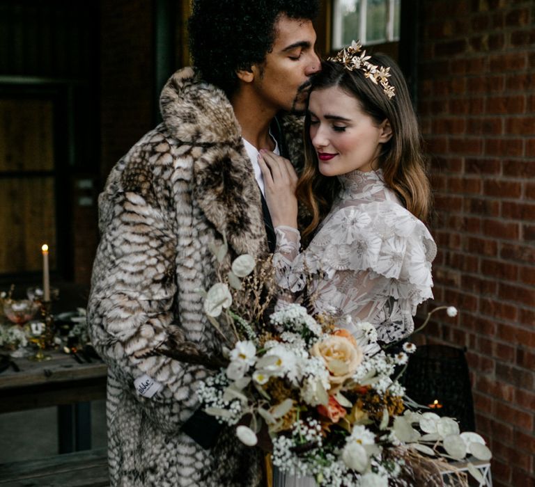 Groom in Faux Fur Coat Kissing His Bride in a High Neck Wedding Dress