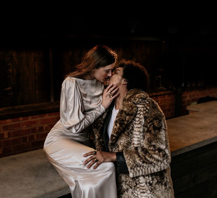 Bride in Satin Wedding Dress with Long Sleeves and Groom in Faux Fur Overcoat