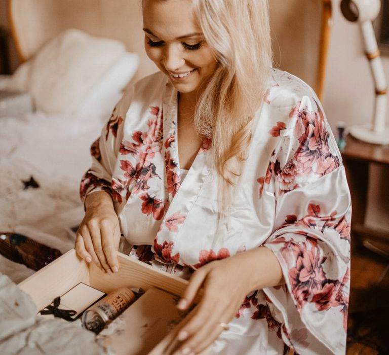 Bride opening a gift box from the groom on the wedding morning