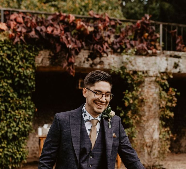 Groom in glasses in navy suit and patterned shirt