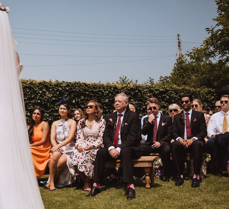 Outdoor Wedding Ceremony with Wedding Guests Sitting on Benches