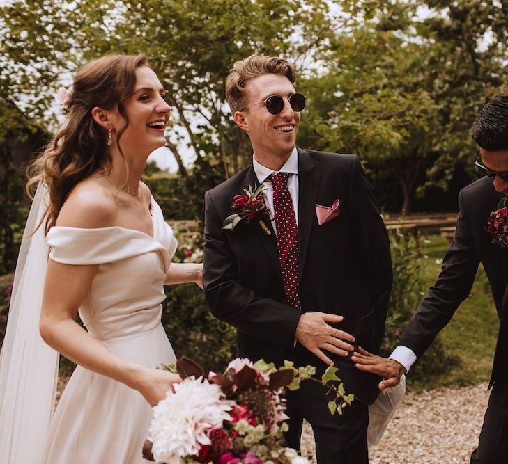 Groomsmen in Black Suits with Burgundy Polka Dot Ties Congratulating The Bride