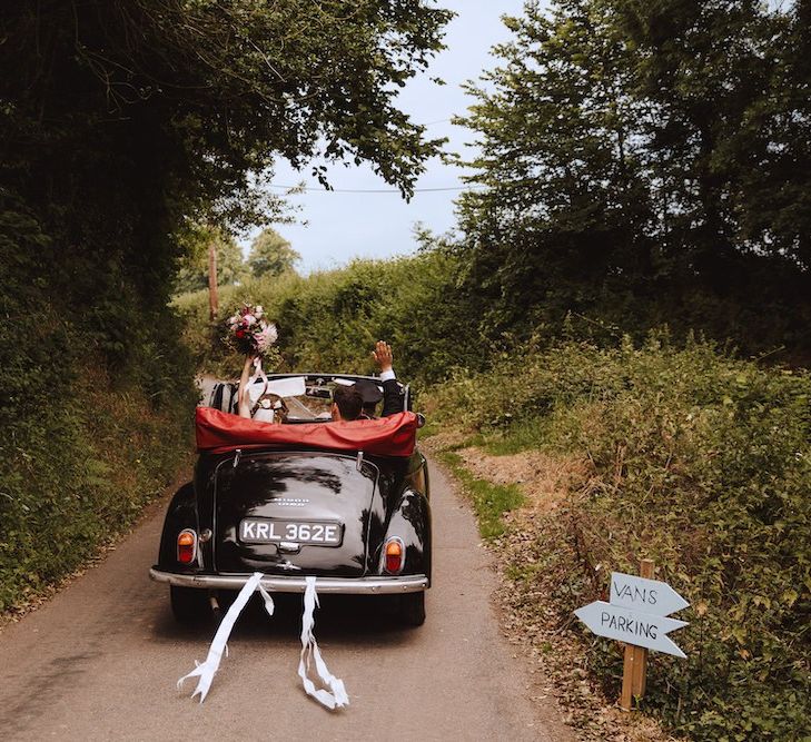 Bride and Groom Driving Off into the Sunset in a Black Vintage Wedding Car