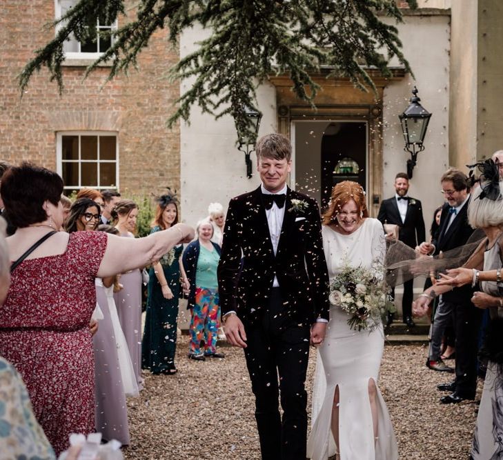 Confetti exit at Aswarby Rectory with bride in Alexandra Grecco wedding dress and groom in tuxedo