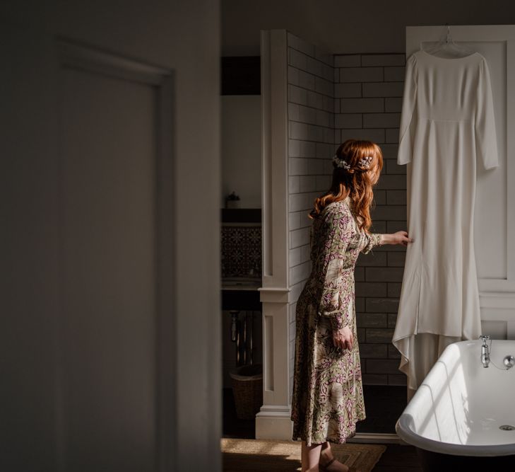 Bride on wedding morning looking at her Alexandra Grecco hanging up