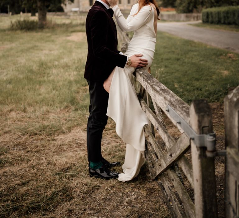 Bride in Alexandra Grecco wedding dress sitting on a gate