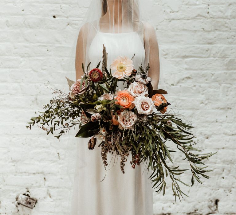 Beautiful Bride in Oversized Bridal Bouquet with Foliage and Peach Flowers