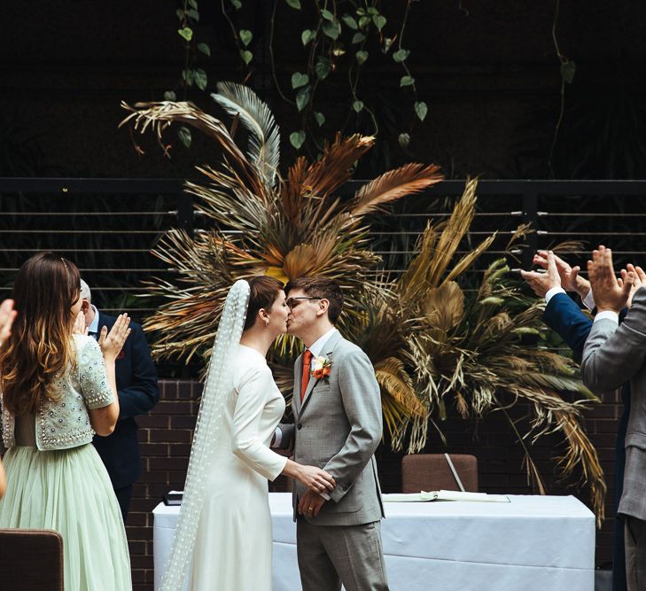 Bride and Groom Kissing at the Altar with Dried Fern Backdrop Flowers