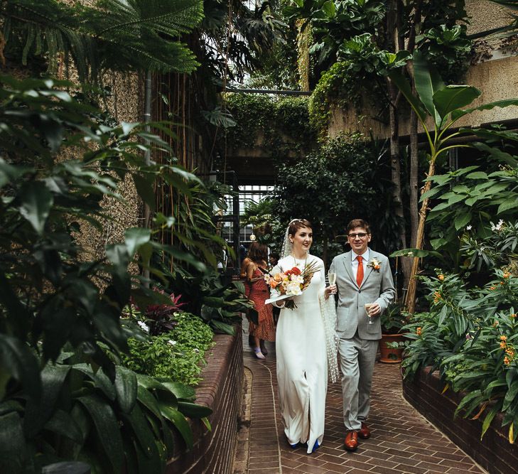 Bride in Charlie Brear Wedding Dress and Groom in Light Grey Suit Walking Around Barbican Conservatory in London