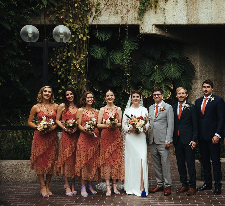 Wedding Party Portrait with Bridesmaids in Polka Dot Sheer Zara Dresses, Bride in Charlie Brear Dress with Long Sleeves, Groom in Light Grey Suit and Groomsmen in Navy Suits with Orange Ties