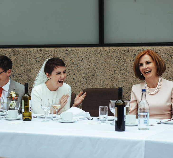 Bride with Pixie Hair Cut Laughing During Wedding Reception Speeches