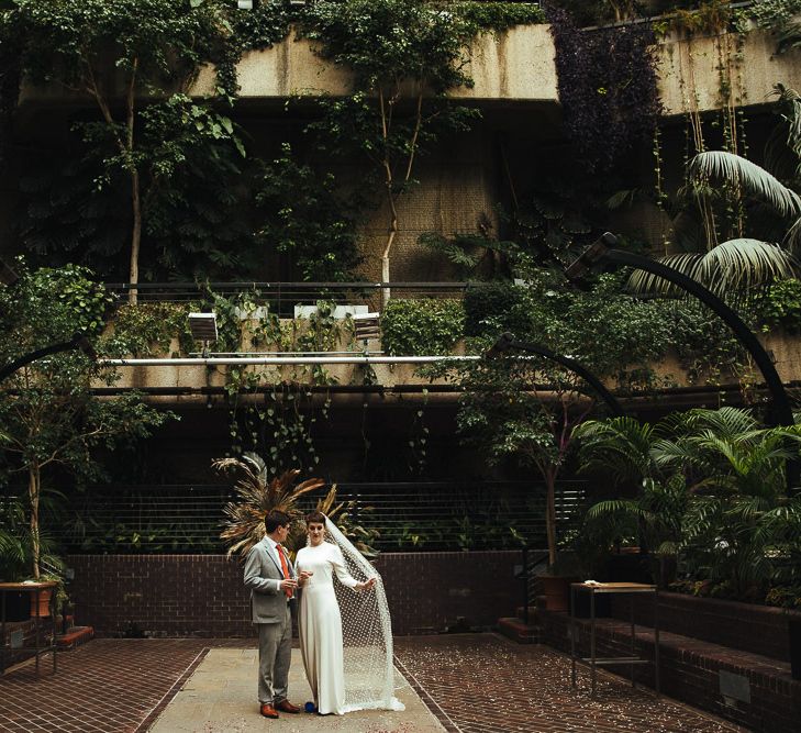 Bride in Charlie Brear Wedding Dress and Polka Dot Wedding Veil and Groom in Light Grey Suit