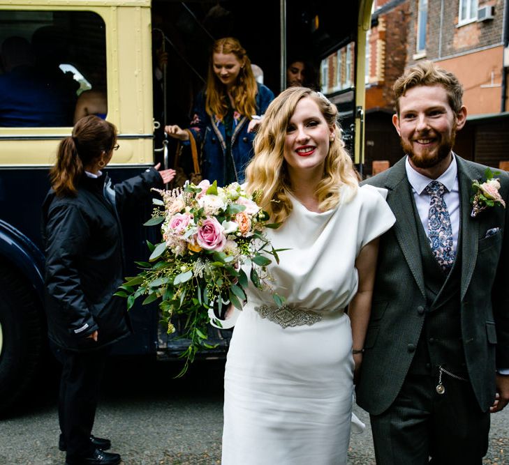 Bride in Vintage Wedding Dress and Groom in Tailored Suit  Getting off Wedding Bus