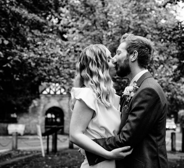 Vintage Bride with Satin Wedding Dress and  Finger Waves Kissing Groom in Tailored Wedding Suit