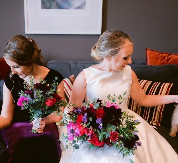 Bride with bridesmaid in plum dresses and family pets at wedding