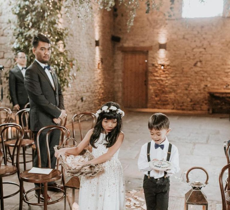 Flower girl and page boy walking down the aisle dropping petals