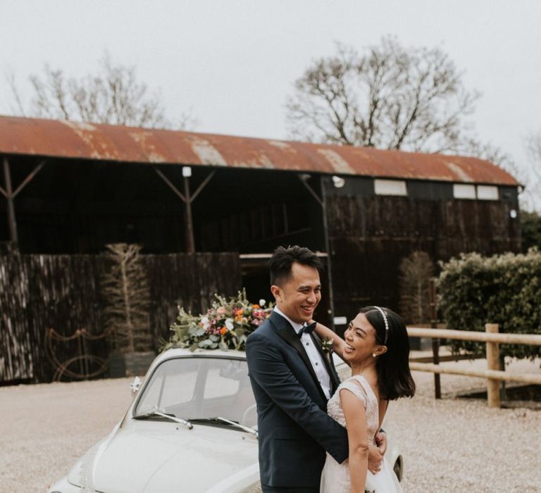 Bride and groom standing next to their Fiat 500 wedding car