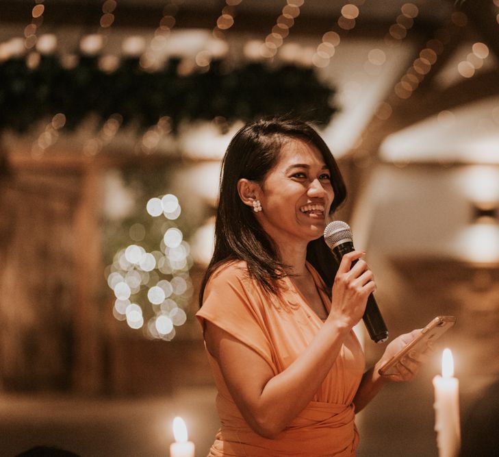 Bridesmaid giving a wedding speech at rustic reception