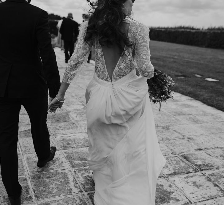 Bride in Donatelle Godart Wedding Dress with Lace V Back &amp; Groom in De Fursac Suit Holding Hands