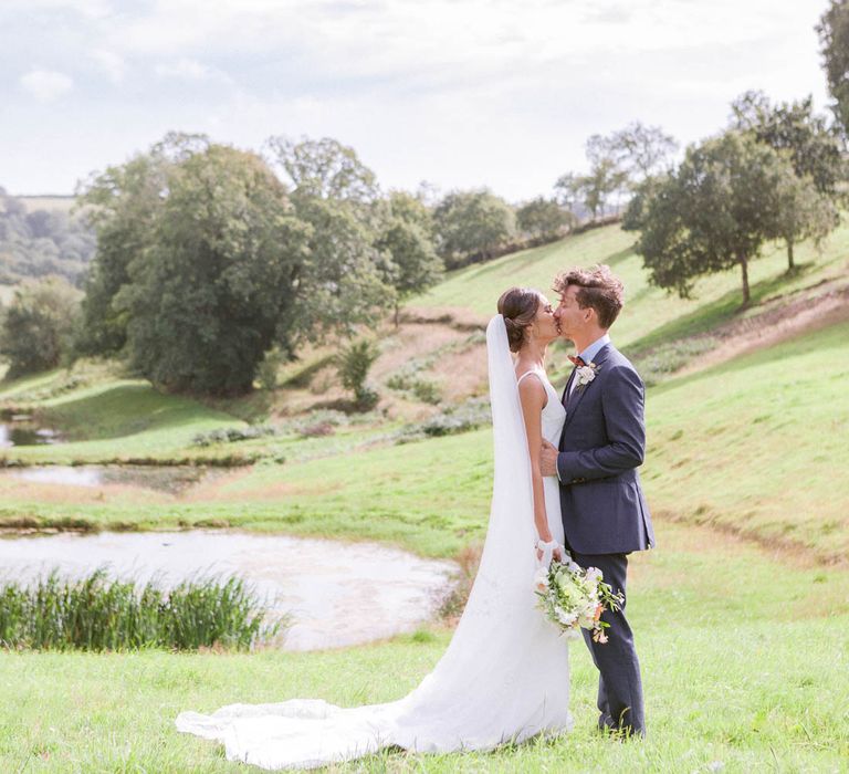 Cathedral veil with lace detail for bride with groom in navy suit and bowtie