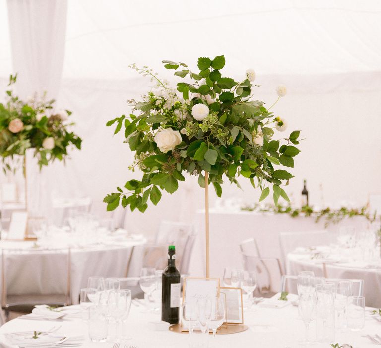 Tall wedding table centrepieces with gold detail and flowers and foliage