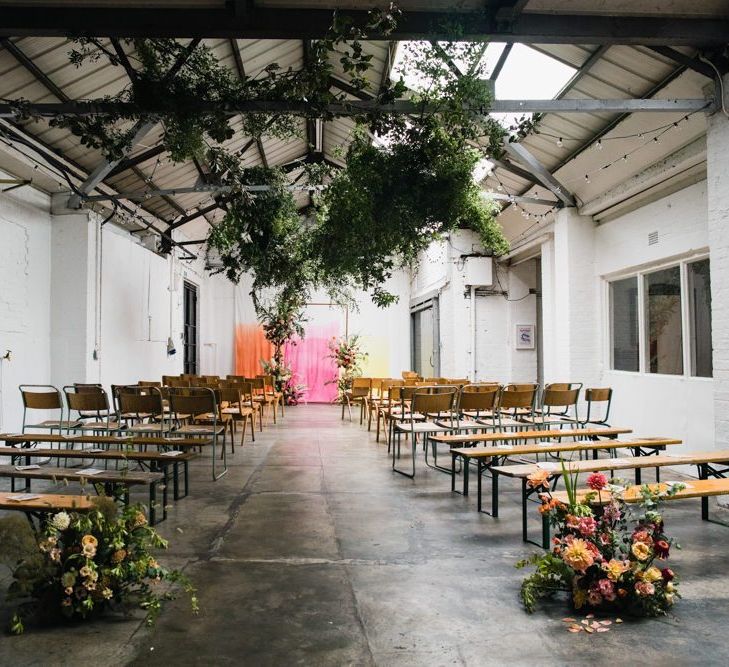 Industrial wedding ceremony with hanging foliage and floral decor