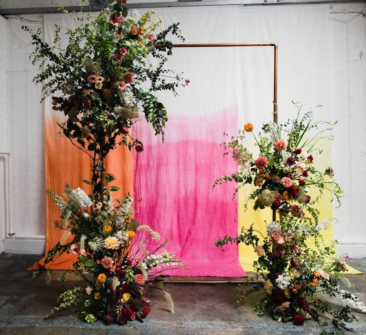 Copper arch with bright floral decor at industrial wedding ceremony