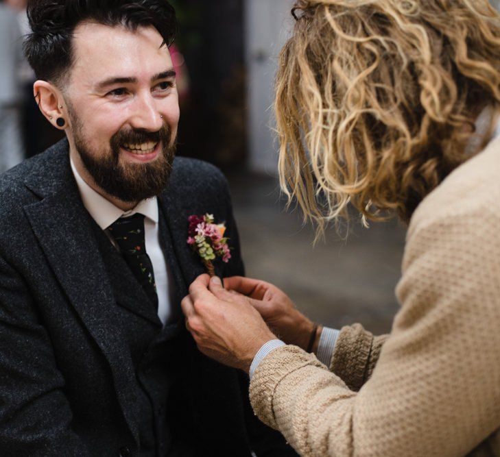 Groom getting ready for wedding ceremony wearing brightly coloured floral buttonhole