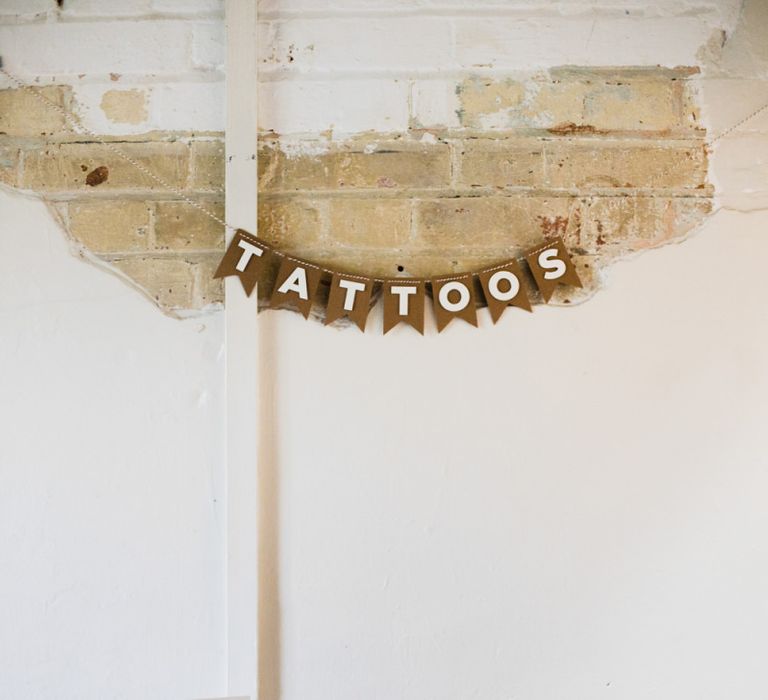 Temporary tattoo station at industrial wedding ceremony hanging sign